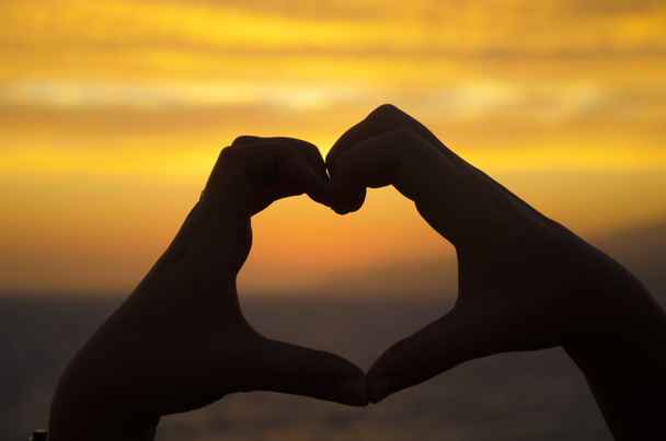 silhouet van hand in hart vorm op zonsondergang - Foto, afbeelding