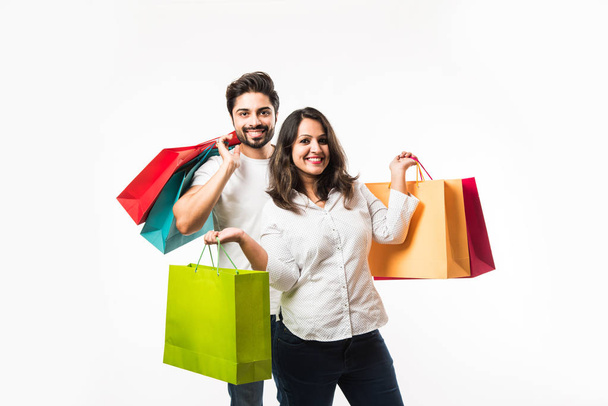 India joven pareja bolsas de compras, de pie aislado sobre fondo blanco. enfoque selectivo
 - Foto, imagen