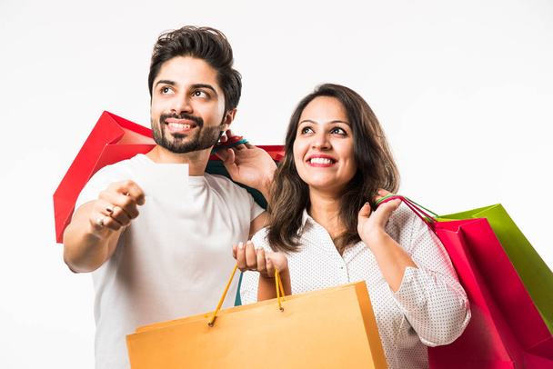 Indické mladé pár nákupních tašek a prázdná debetní/kreditní nebo elektronická karta pro platbu, stojící izolovaně na bílém pozadí. selektivní zaměření - Fotografie, Obrázek
