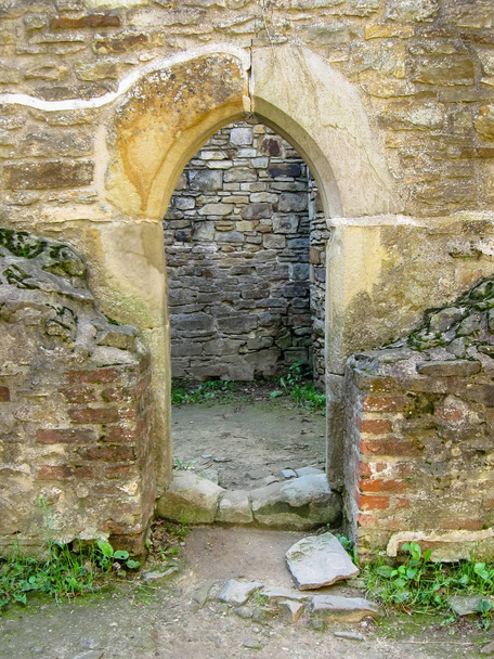 Portal estilo gótico entre paredes de pedra e tijolo
 - Foto, Imagem