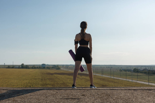 schöne schlanke athletische Mädchen führt eine Reihe von Übungen im Freien durch. ein Gefühl der Freiheit vom Yoga. - Foto, Bild