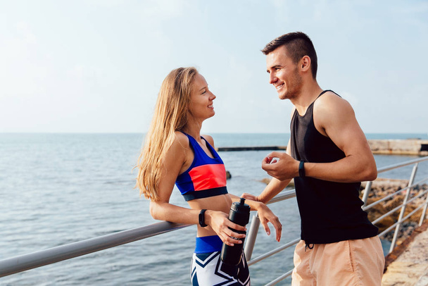 Cheerful sportive couple talking each other during break after workout - Foto, Bild