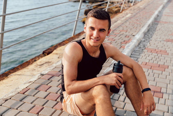 Smiling sportsman drinking a water after running - Foto, Imagem