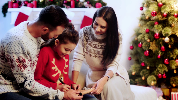 radosny dziecko piśmie do Santa w pobliżu rodziców  - Materiał filmowy, wideo