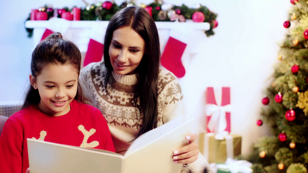 happy mother and daughter reading book on christmas  - Metraje, vídeo