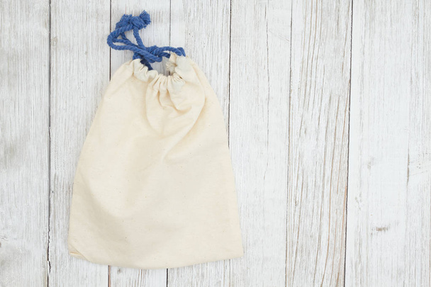 Bolso de lona beige en fondo de madera texturizada blanqueada
 - Foto, imagen