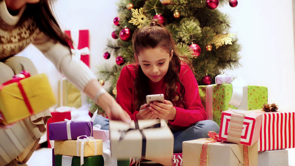 kid using smartphone near presents and parents - Filmagem, Vídeo