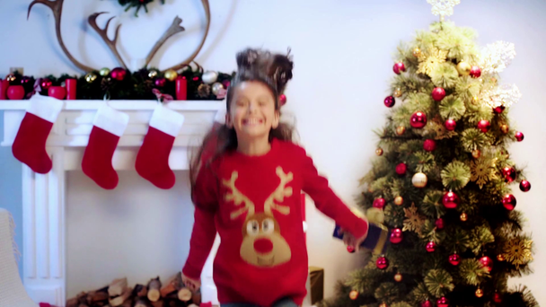 Zeitlupe eines fröhlichen Kindes, das mit Geschenk springt  - Filmmaterial, Video