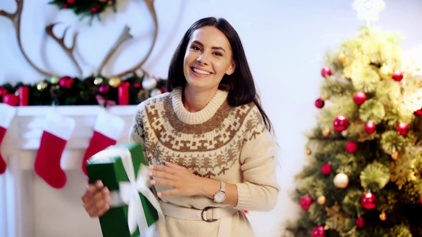 mujer feliz sosteniendo presente cerca del árbol de Navidad
  - Imágenes, Vídeo
