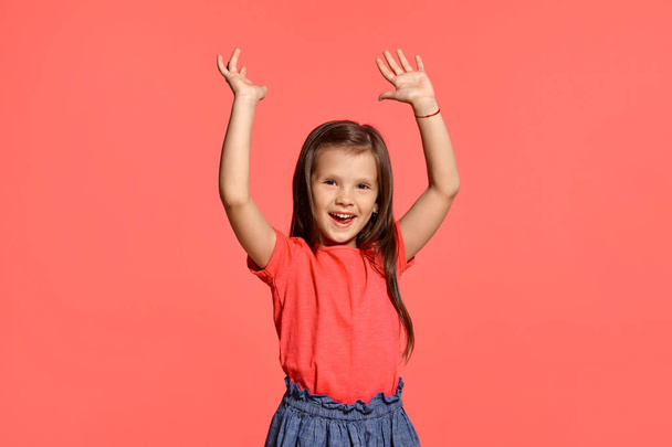 Close-up studio shot of beautiful brunette little girl posing against a blue background. - Foto, Imagen