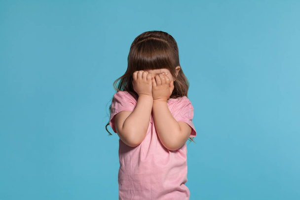 Красива маленька дівчинка в рожевій футболці позує на синьому студійному фоні
. - Фото, зображення