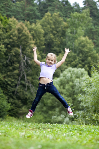 Happy little girl jumping in summer day - Foto, afbeelding