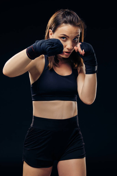 Femme athlétique en mitaines de boxe pratique le karaté en studio
. - Photo, image