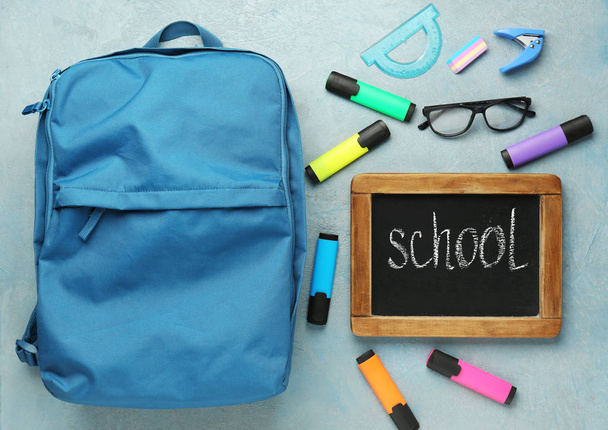 Backpack with supplies and chalkboard with word SCHOOL on grey background - Fotoğraf, Görsel