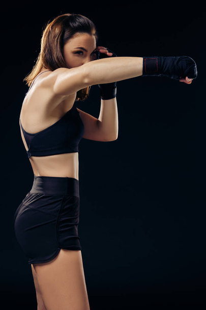 Αθλητική γυναίκα στο μποξ γάντια είναι εξάσκηση καράτε σε στούντιο. - Φωτογραφία, εικόνα