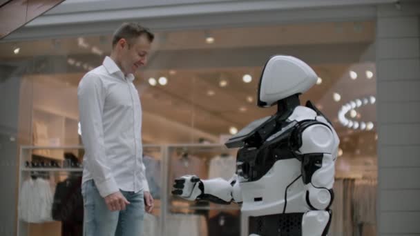 ein Mann im Hemd kommuniziert mit einem weißen Roboter, der Fragen stellt und mit den Fingern auf den Bildschirm drückt. - Filmmaterial, Video