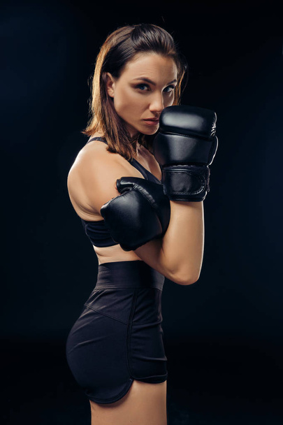 Athletic woman in boxing gloves is practicing karate in studio. - Foto, Bild