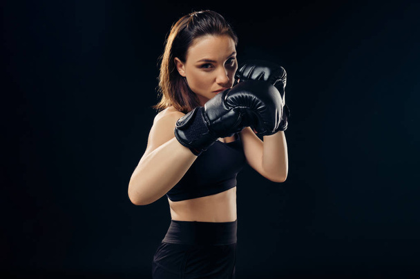 Atletyczna Kobieta w rękawicach bokserskich uprawia karate w studiu. - Zdjęcie, obraz
