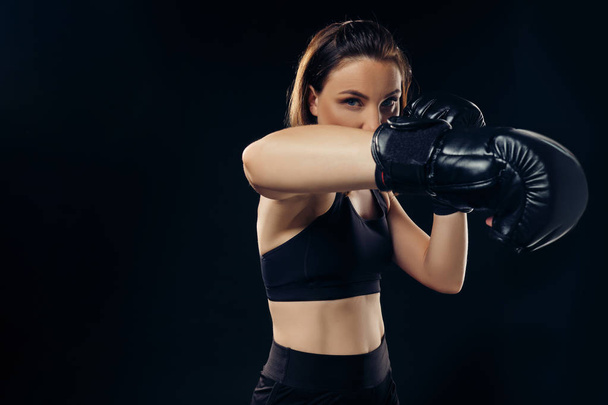 Спортивная женщина в боксёрских перчатках занимается карате в студии
. - Фото, изображение