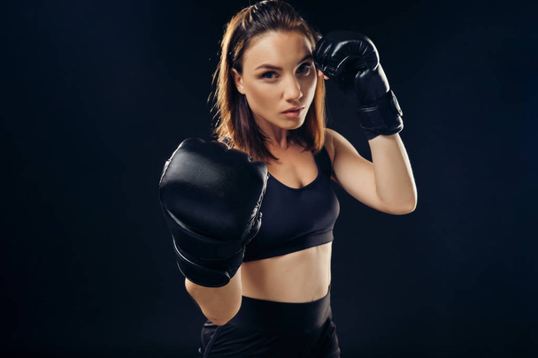 Athletic woman in boxing gloves is practicing karate in studio. - Photo, Image