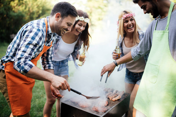 Friends having a barbecue party in nature while having fun - Foto, Bild