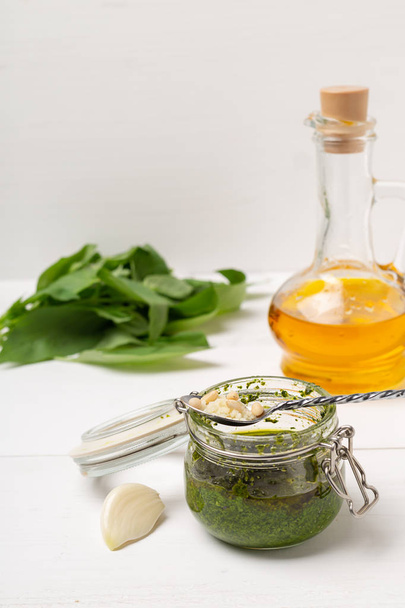 Jar with basil pesto sauce on table - Zdjęcie, obraz