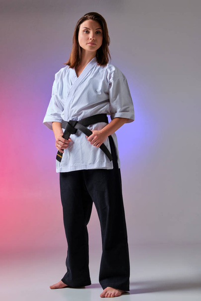 Urheilullinen nainen perinteisessä kimonossa harjoittelee karatea studiossa
. - Valokuva, kuva
