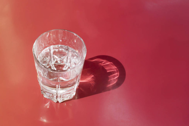 Glass of water on the red-orange table with copy space - Foto, immagini