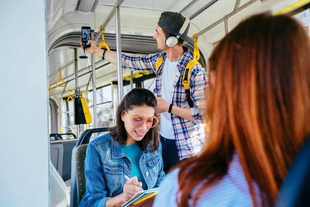 Fiatal gyönyörű nő napszemüveg a fejét hajlik a buszsáv és a gazdaság rá a poggyász táska utazás közben busszal. - Fotó, kép