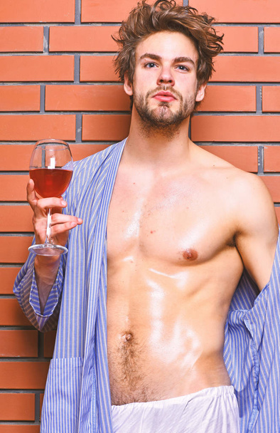 Drink wine and relax. Erotic and desire concept. Guy attractive relaxing with alcohol drink. Man sexy chest sweaty skin hold wineglass. Bachelor enjoy wine. Macho tousled hair degustate luxury wine - Foto, immagini