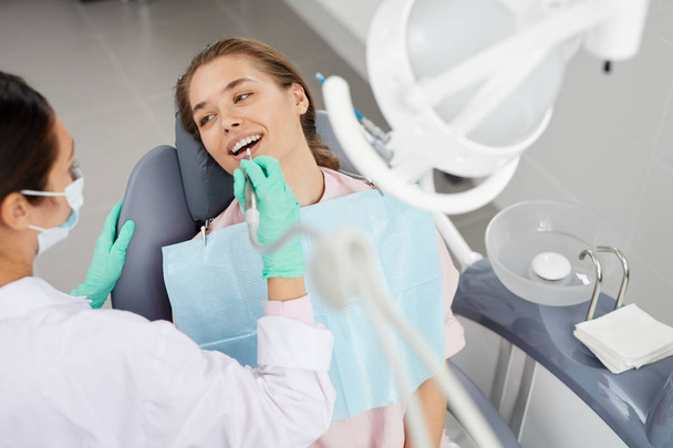 Nagy látószögű portré a gyönyörű fiatal nő fogászati széken során orvosi ellenőrzés fel, másolni tér - Fotó, kép