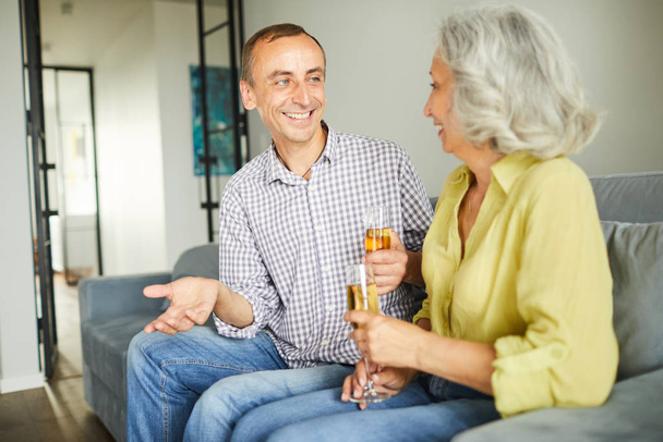 Portrait of happy mature couple drinking champagne while chatting during party, copy space - Photo, image