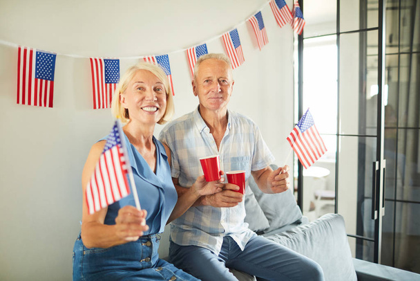 Portrét veselého staršího páru mávající americkou vlajkou a usmívající se na kameru, kopírovat prostor - Fotografie, Obrázek