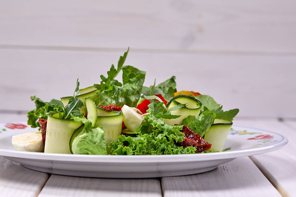 kesäkurpitsa rullina tuoretta salaattia valkoisella lautasella, lähikuva
  - Valokuva, kuva