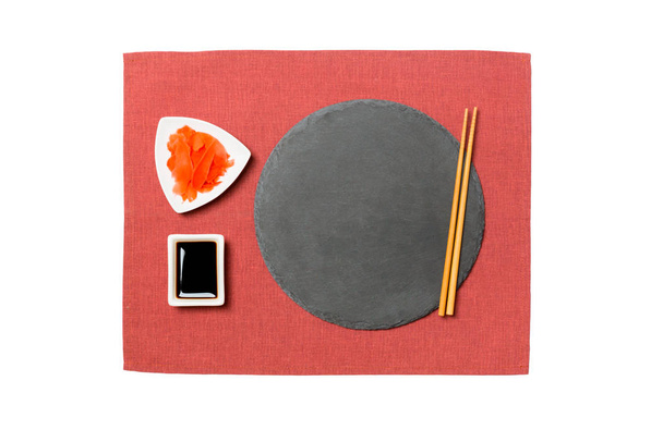 Emptyround fekete pala, pálcikaa sushi, gyömbér és szójaszósz a piros szalvéta háttér. Felülnézet másolási területtel a tervezéshez - Fotó, kép