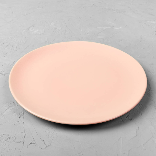 Placa redonda cor-de-rosa ou coral vazia no fundo da mesa de cimento cinza. Visão superior, modelo para o seu design
 - Foto, Imagem