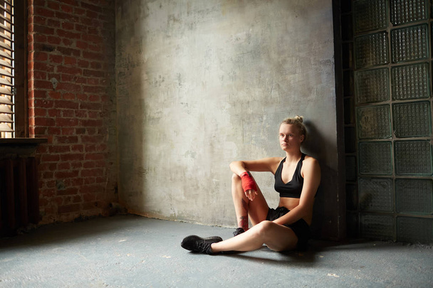 Δραματική ευρεία γωνία πορτρέτο της σκληρής αθλητική γυναίκα που κάθεται από τσιμεντένιο τοίχο, αντίγραφο χώρου - Φωτογραφία, εικόνα