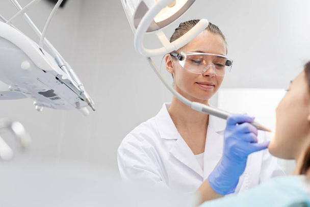 Low angle portrait of smiling female dentist working with patient in clinic, copy space - Fotoğraf, Görsel
