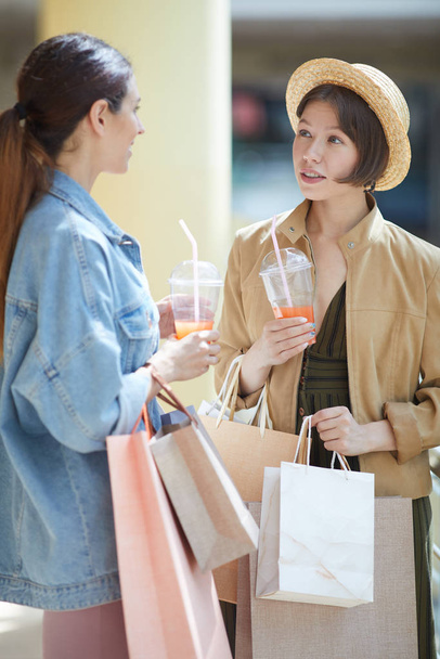 Pozytywne ładne dziewczyny w casual stroje picia świeżego soku, podziwiając przerwę podczas zakupów - Zdjęcie, obraz