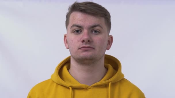 Young handsome smart man wearing yellow sweatshirt over isolated white background afraid and shocked with surprise expression, fear and excited face. Problem skin and acne. - Filmagem, Vídeo