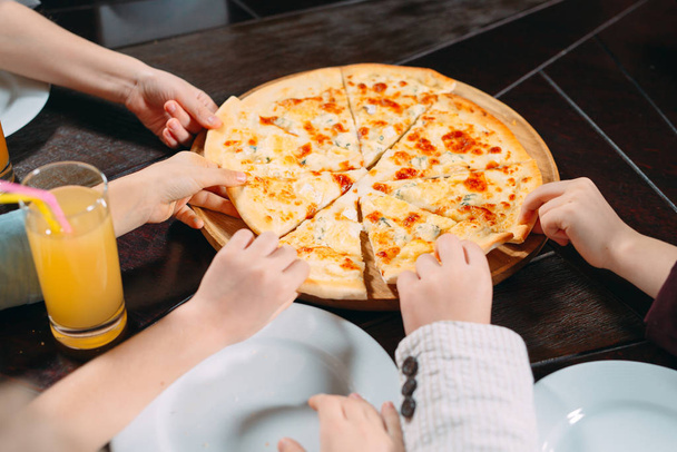 Hands taking pizza slices from wooden table, close up view - Foto, Imagen