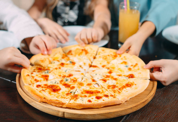 Hands taking pizza slices from wooden table, close up view - Foto, Imagen