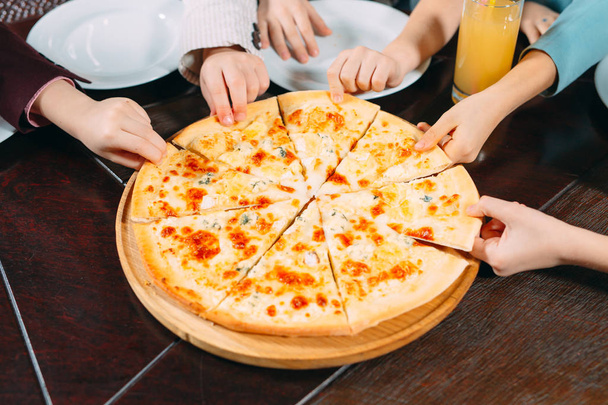 Hands taking pizza slices from wooden table, close up view - Фото, изображение