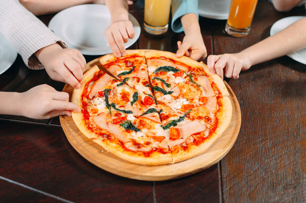Hands taking pizza slices from wooden table, close up view - Foto, afbeelding