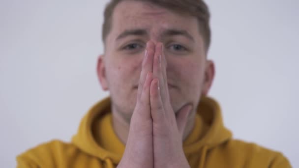 Portrait of young man folded his hands in prayer close-up. The guy is worrying, trying to calm himself. Concept of emotions, guy in trouble. Problem skin and acne. - Materiał filmowy, wideo