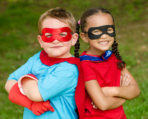 Pretty mixed race girl and Caucasian boy pretending to be superhero - Фото, изображение