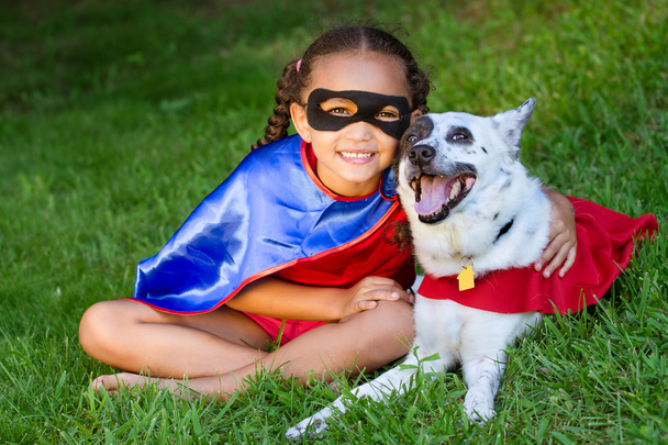 Melko sekarotuinen tyttö halaamalla hänen lemmikki sekä pukeutunut super sankari puvut
 - Valokuva, kuva