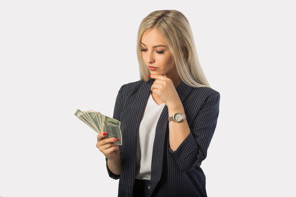 beautiful young woman in a suit on a white background with dollars in hands - Fotoğraf, Görsel