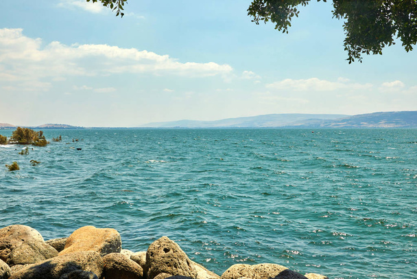 Vista do Mar da Galiléia com um barco de recreio do lado leste em um dia ensolarado de verão, julho
 - Foto, Imagem