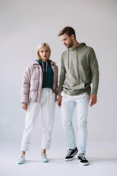 full length view of stylish blonde girl and bearded man on grey - Foto, afbeelding